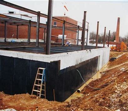 A concrete foundation is shown with partial completion of application of a waterproofing product.