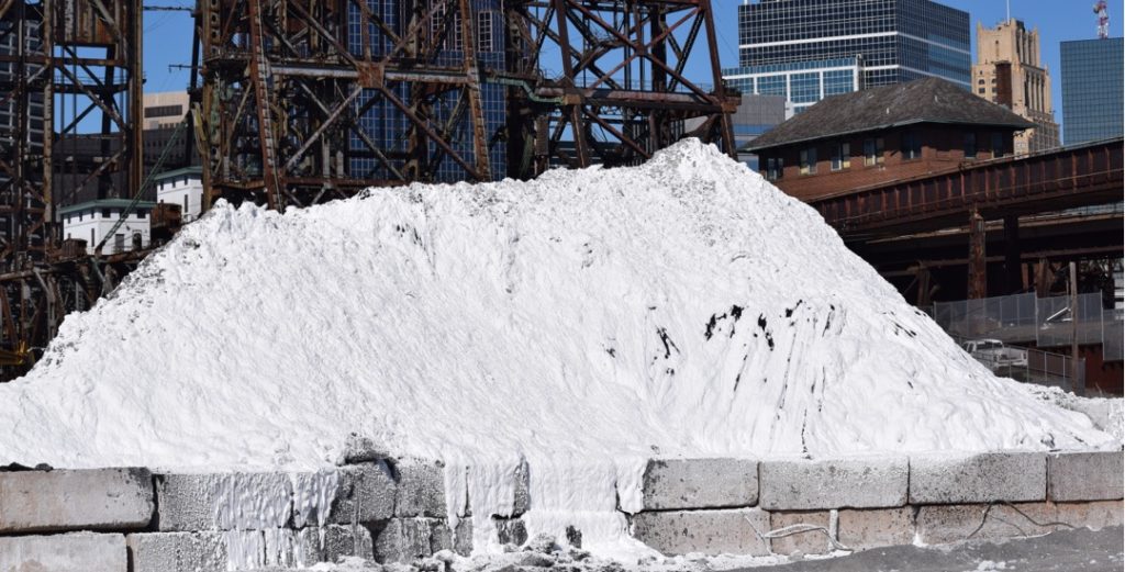 White foam covers a pile of polluted topsoil at an environmental remediation site.